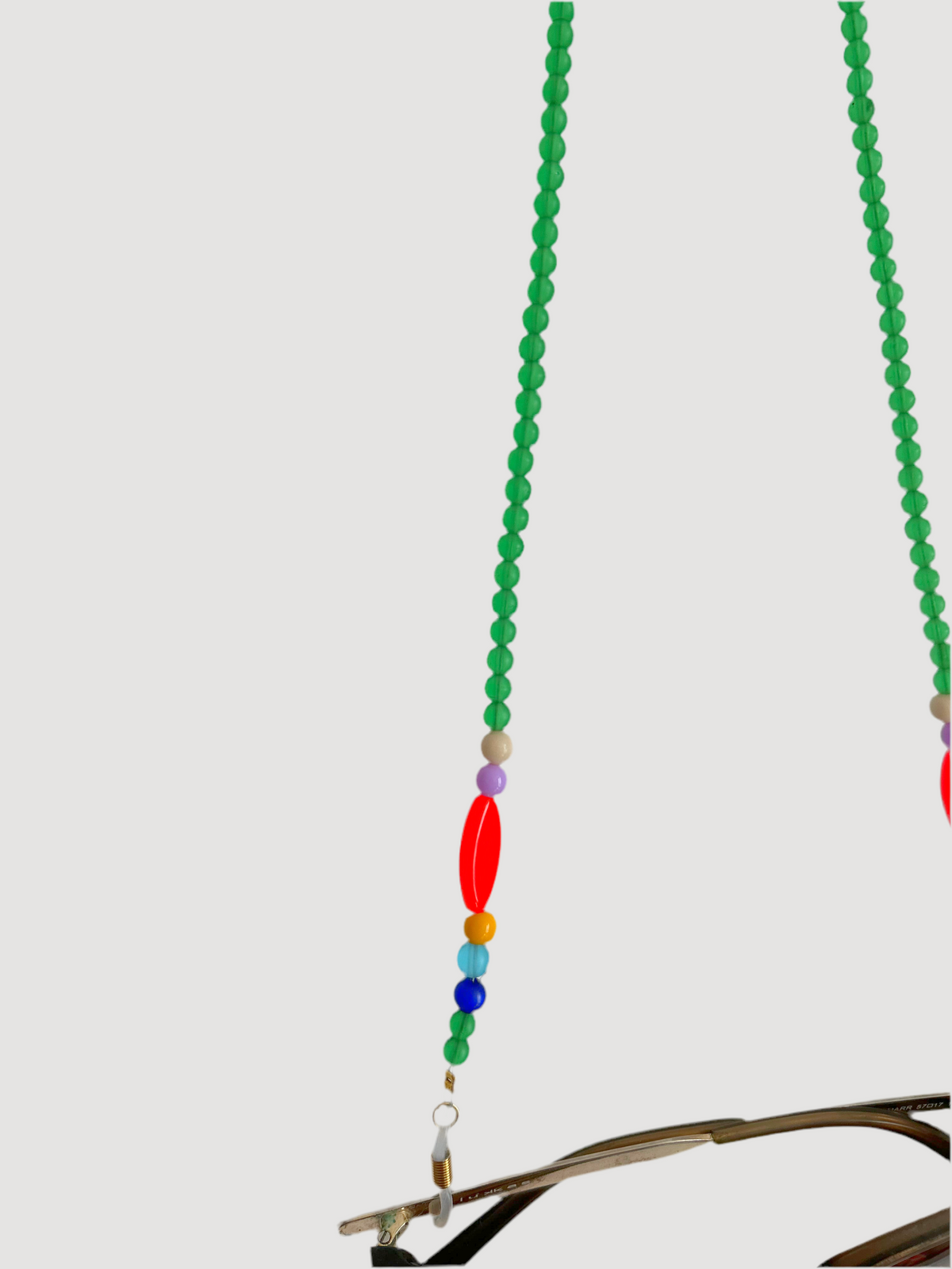 Détail de la chaîne de lunettes en perles vertes, perle rouge ovale et petites perles colorées
