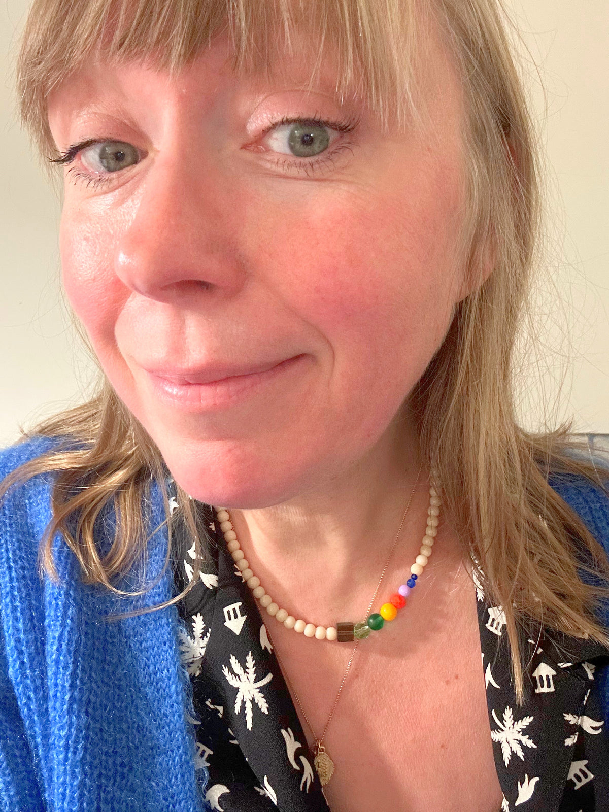 Collier ras du cou en perles de verre beige et arc-en-ciel porté au cou