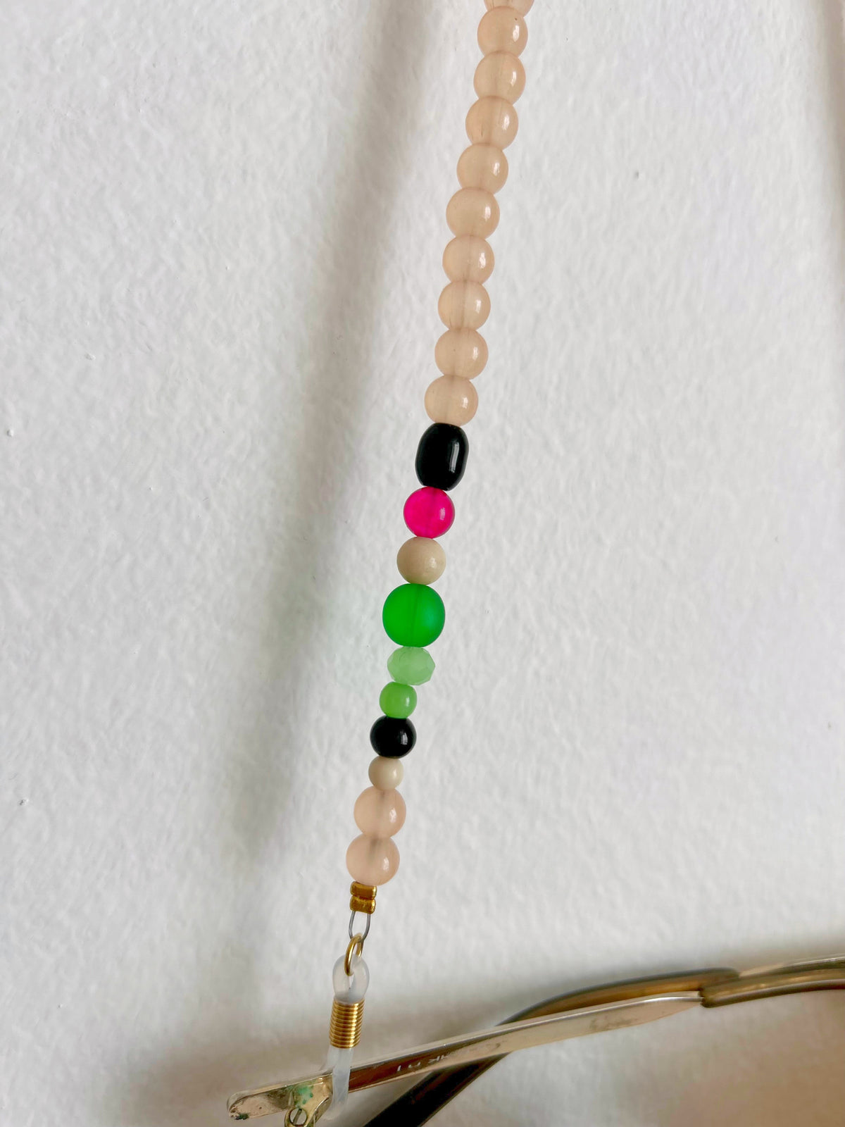 Détail des perles noires, vertes et roses de la chaîne de lunettes marron glacé