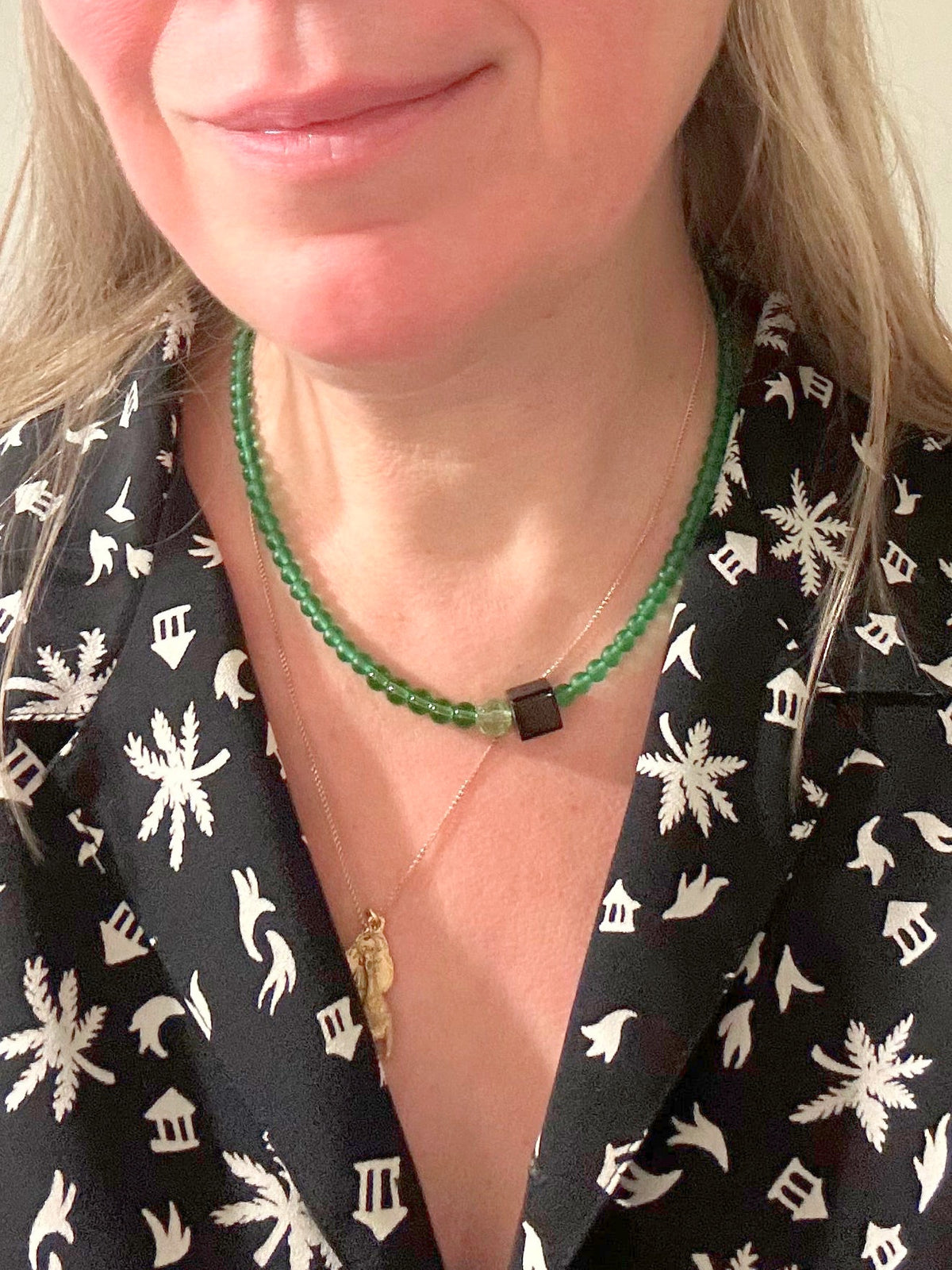 Collier ras du cou en perles de verre vert avec perle noire, porté au cou