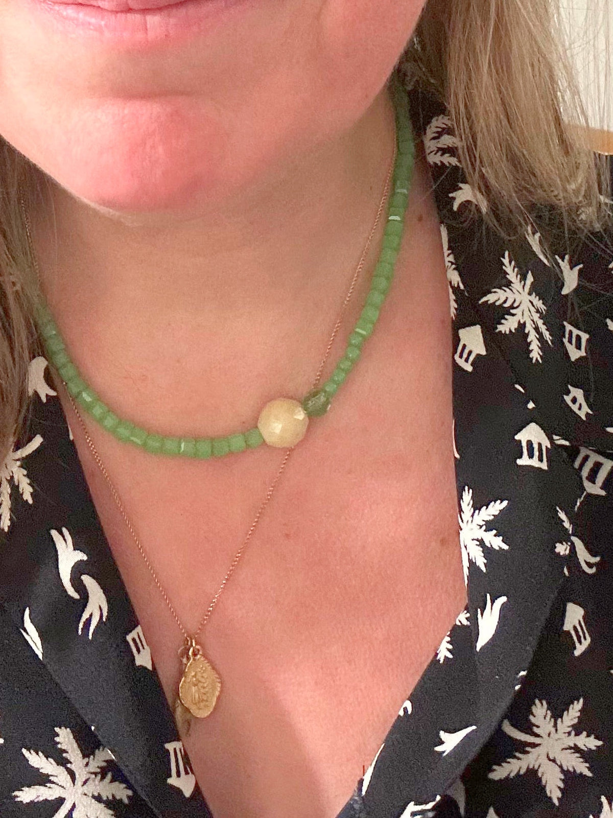 Collier ras du cou en perles de verre vert et beige porté au cou