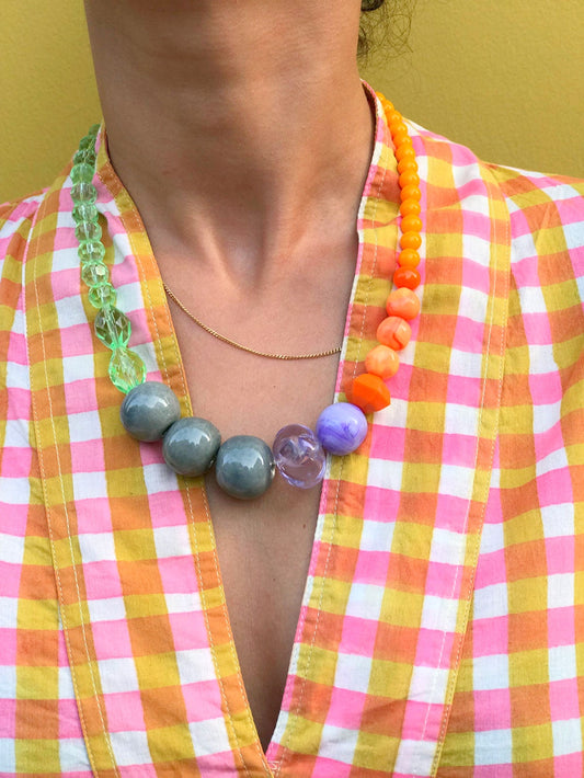 Collier en grosses perles orange et vertes porté avec une chemise à carreaux