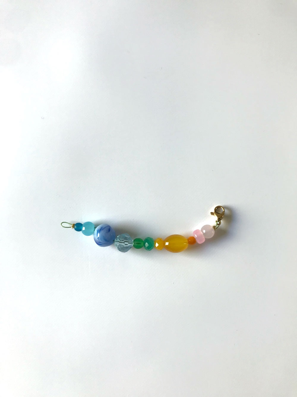 Pendentif extension de chaîne n°2, perles bleues, turquoise, jaune et rose, sur fond blanc