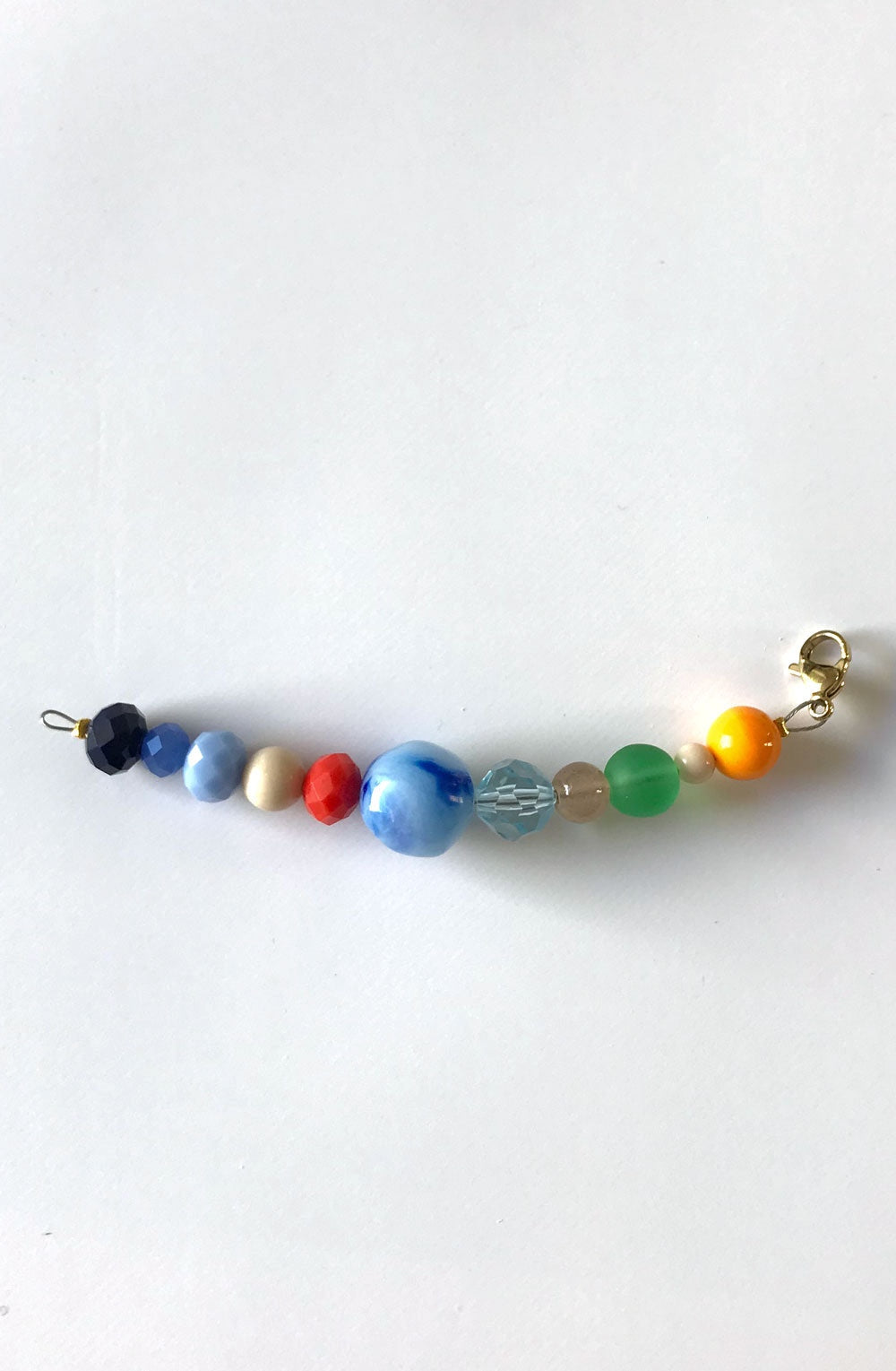 Pendentif extension de chaîne n°5, perles bleues, rouge, orange et verte, sur fond blanc