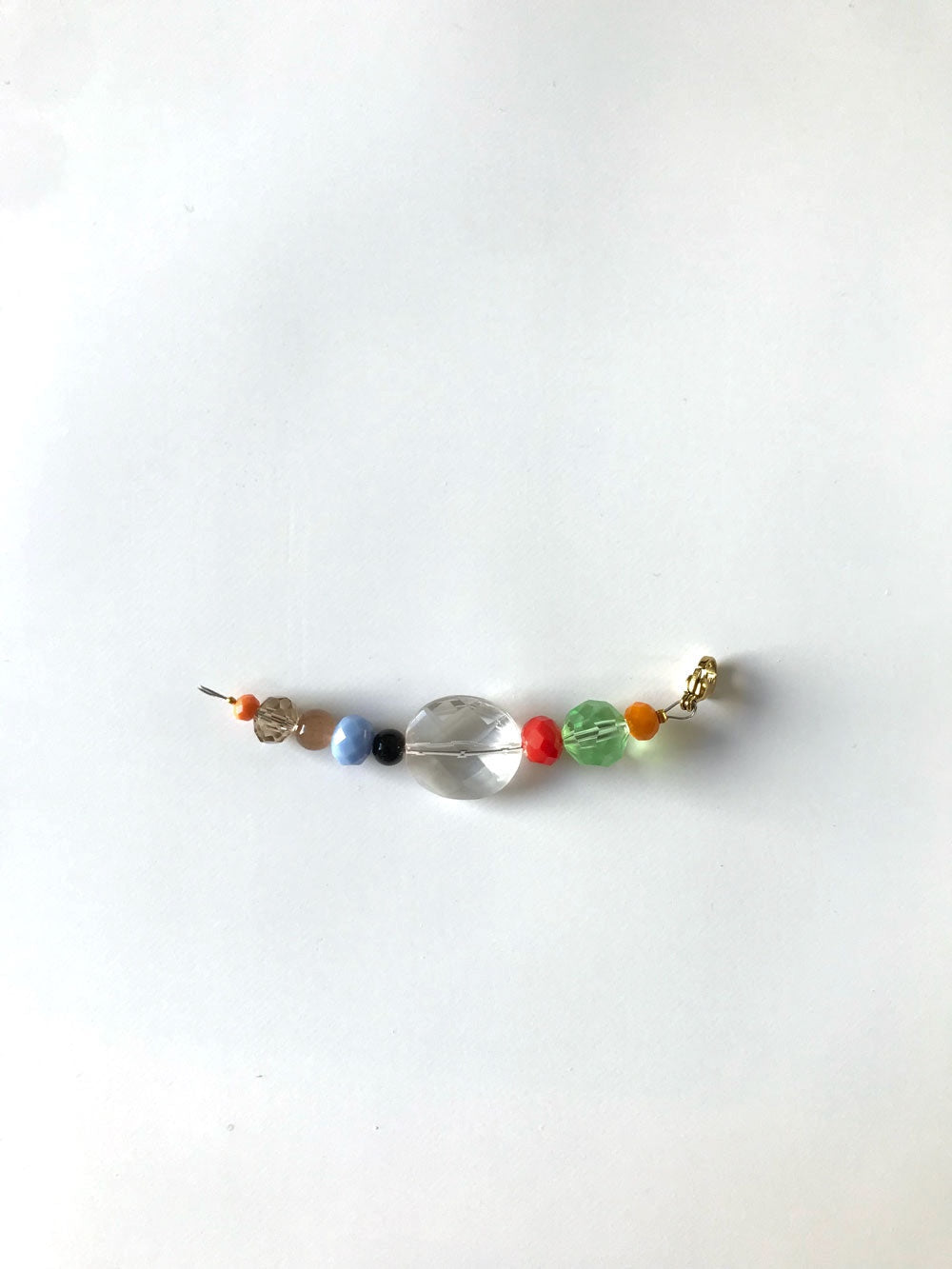 Pendentif extension de chaîne n°7, perles bleues, rouge et grosse perle transparente, sur fond blanc