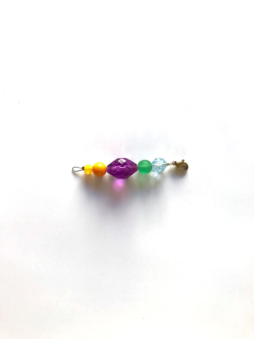 Pendentif extension de chaîne n°8, perles violette, verte et transparente, sur fond blanc