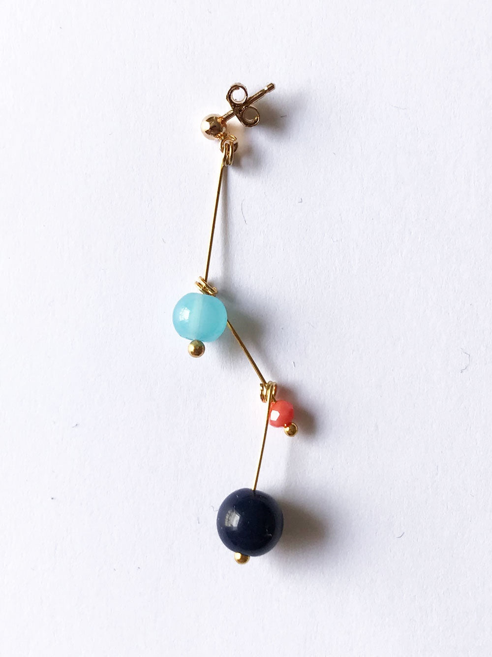 Petite boucle d'oreille mobile n°13, perles turquoise, rouge et bleu nuit, sur fond blanc
