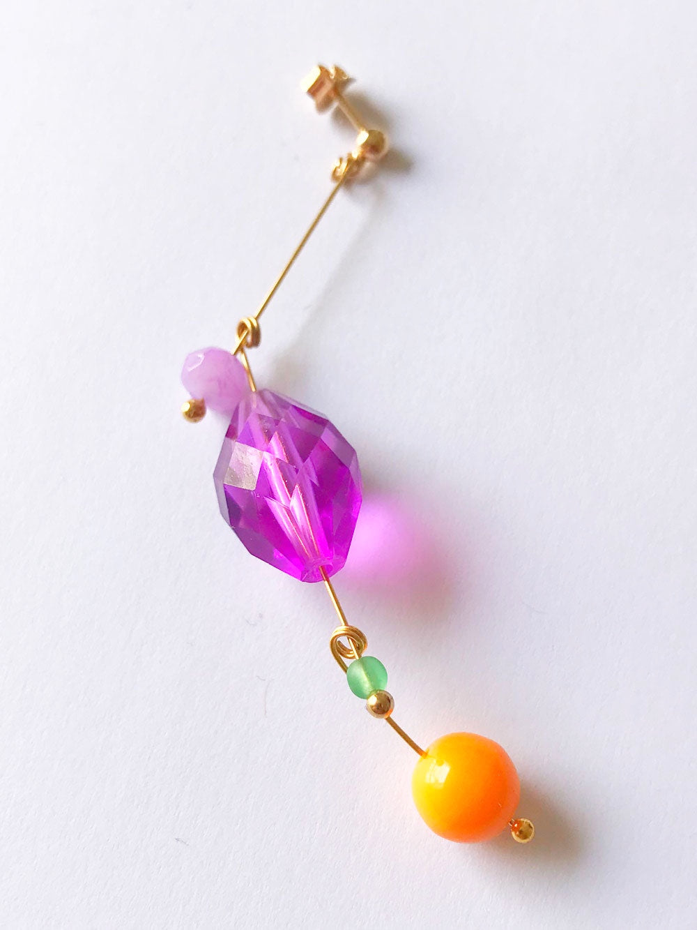Petite boucle d'oreille mobile n°7, perles violette facettée, verte et orange, sur fond blanc
