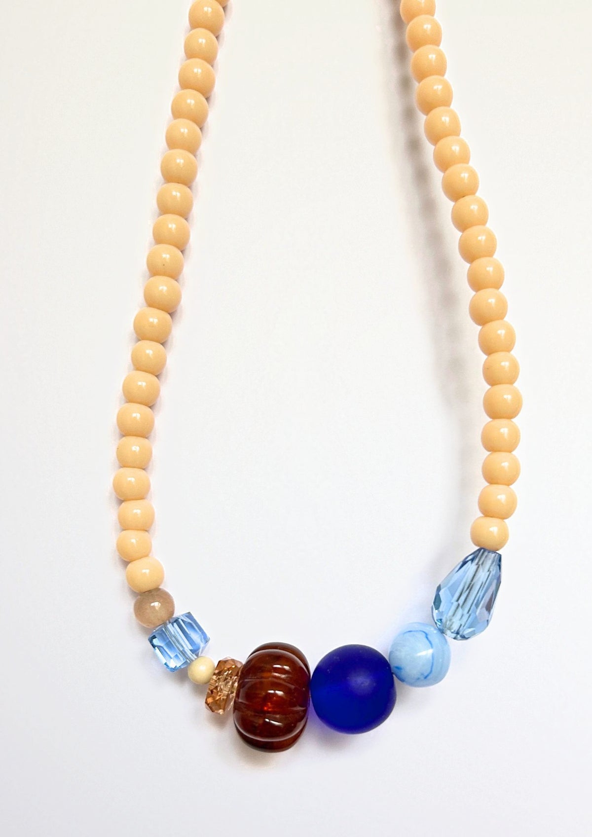 Détail du collier Maison Chouquette : perle côtelée marron ambré, grosse perle bleu roi givrée, perle bleu ciel marbrée et gouttes bleu glacier facettées