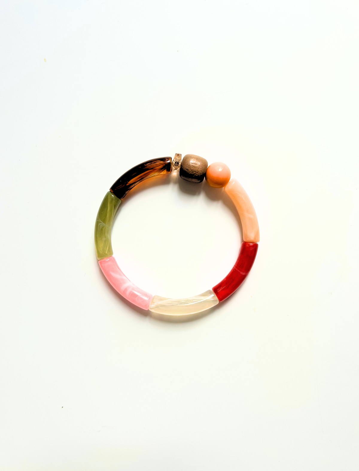 Petit bracelet pièce unique n°10 en perles tubes écaille, kaki, rose, crème, rouge et pêche, perle en bois, perle ronde pêche et perle ambrée, posé sur fond blanc