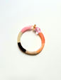 Petit bracelet pièce unique n°13 en perles tubes rose, crème, marron, taupe, pêche et corail, perle rose facettée et perle ambrée, posé sur fond blanc