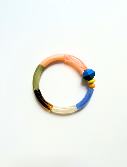 Petit bracelet pièce unique n°15 en perles tubes pêche, corail, kaki, écaille, crème et bleu, perle bleue et noire facettée, perles jaune et orange, posé sur fond blanc