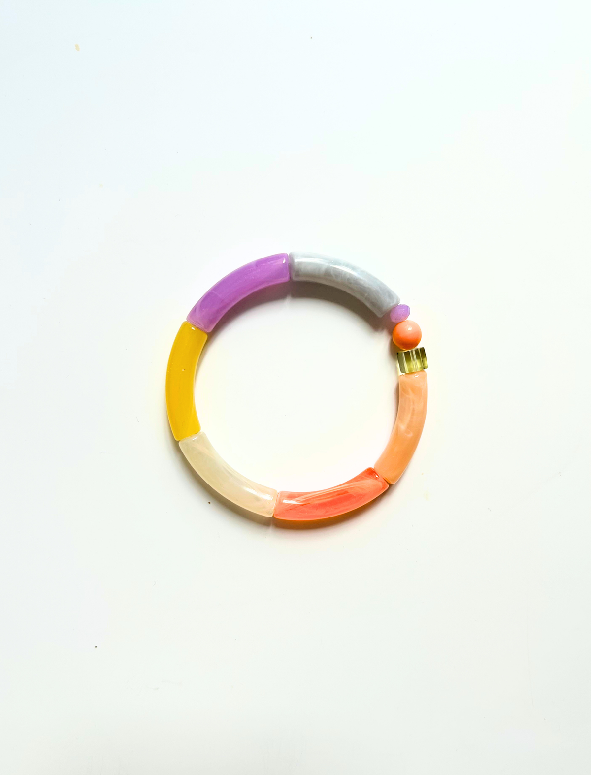 Petit bracelet pièce unique n°17 en perles tubes lavande, gris, jaune, crème, corail et pêche, perle ronde corail, perle lavande et cube olive, posé sur fond blanc