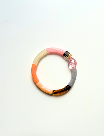 Petit bracelet pièce unique n°6 en perles tubes rose, crème, corail, pêche, écaille et gris, perle rose facettée, cube fumé et perle dorée, posé sur fond blanc