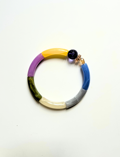 Petit bracelet pièce unique n°9 en perles tubes jaune, lavande, kaki, crème, gris et bleu, perle violette et perles ambrées facettées, posé sur fond blanc