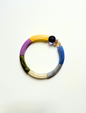 Petit bracelet pièce unique n°9 en perles tubes jaune, lavande, kaki, crème, gris et bleu, perle violette et perles ambrées facettées, posé sur fond blanc