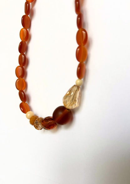 Collier de perles ambre et marron : gros plan sur la grosse perle marron, les facettes ambre et la goutte champagne