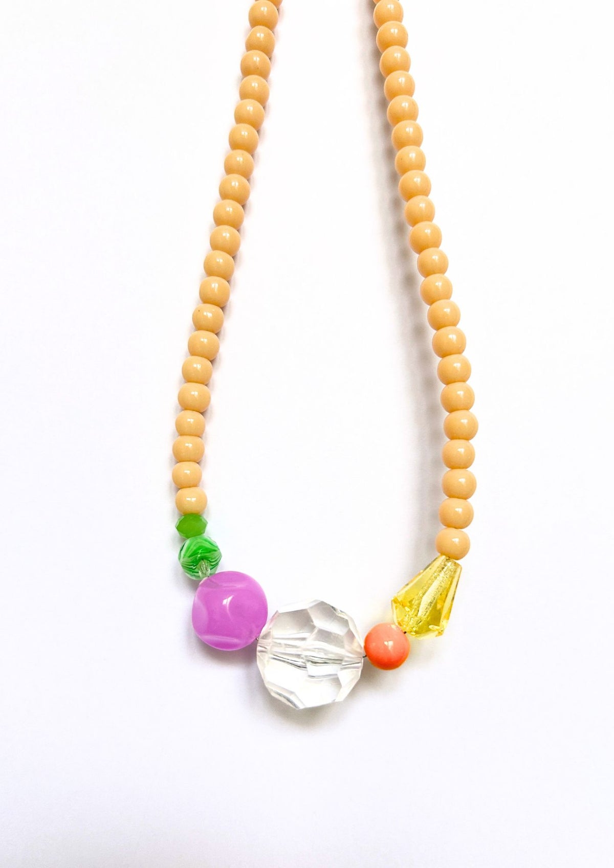 Collier de perles beige et multicolore : gros plan sur le cristal transparent, la perle rose, les perles vertes et la goutte jaune