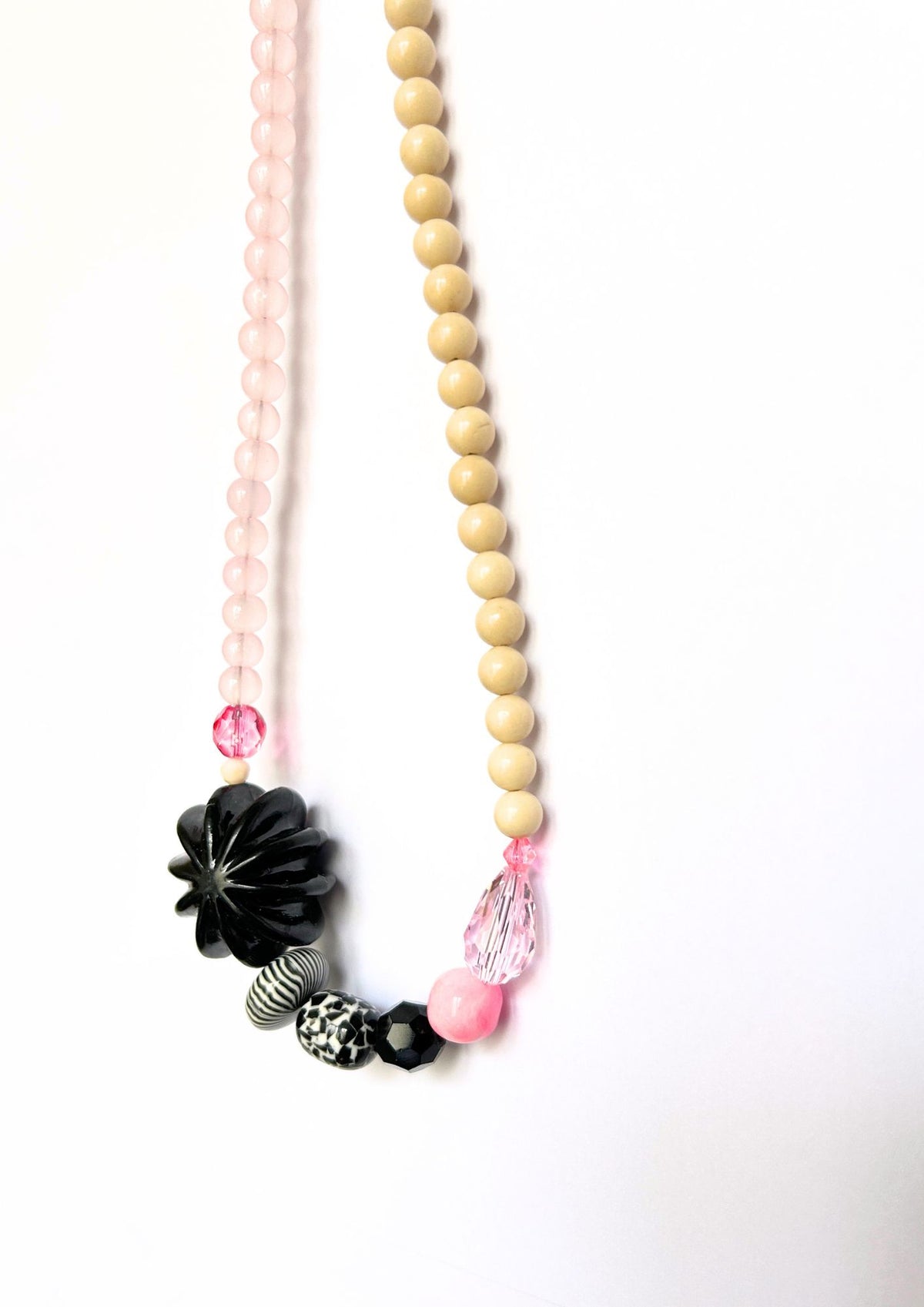 Collier de perles beige, rose et fleur noire : gros plan sur la fleur noire et les perles noir et blanc