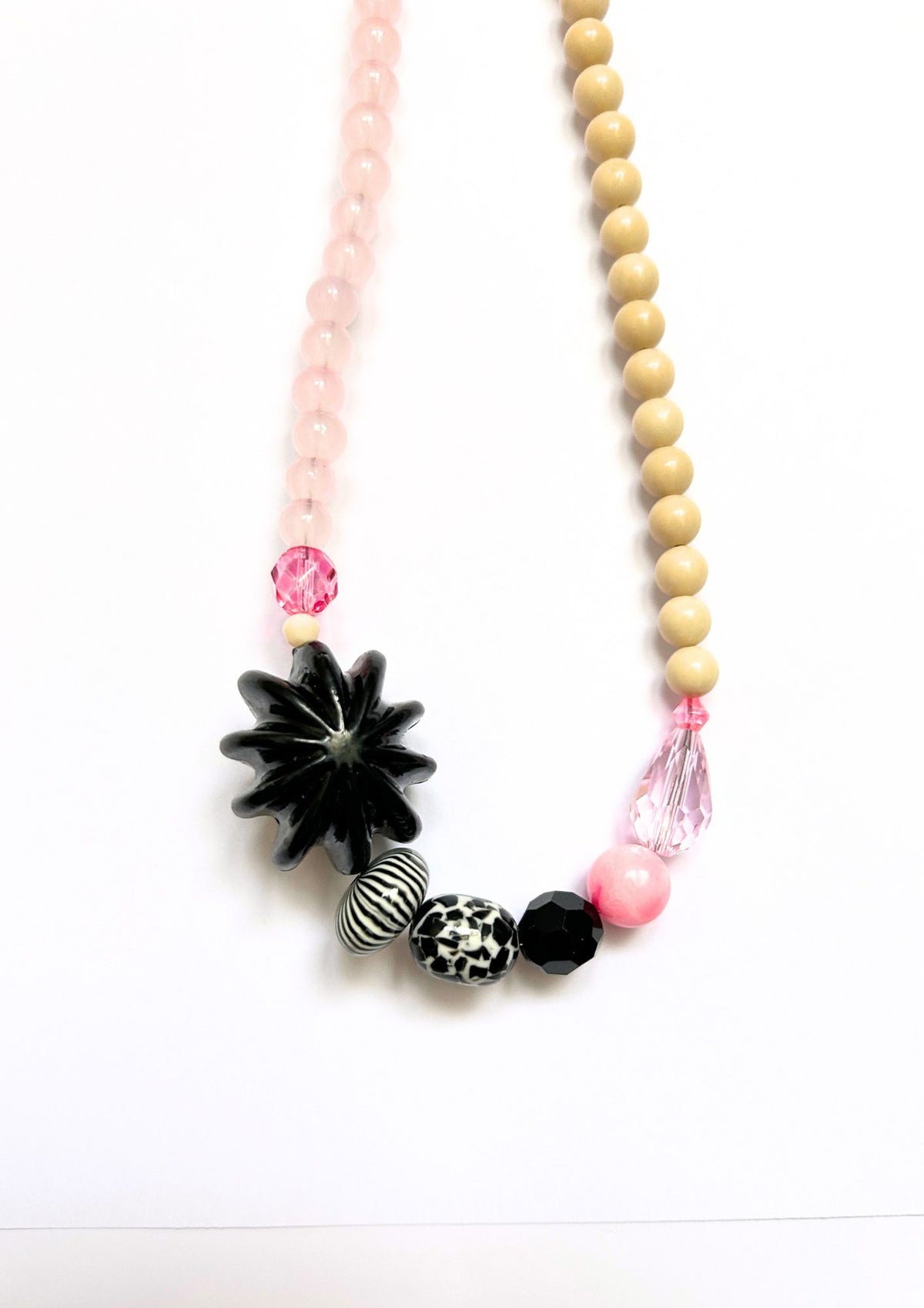 Collier de perles beige, rose et fleur noire : détail de la fleur noire, des perles rayées et de la goutte rose