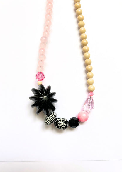 Collier de perles beige, rose et fleur noire : détail de la fleur noire, des perles rayées et de la goutte rose